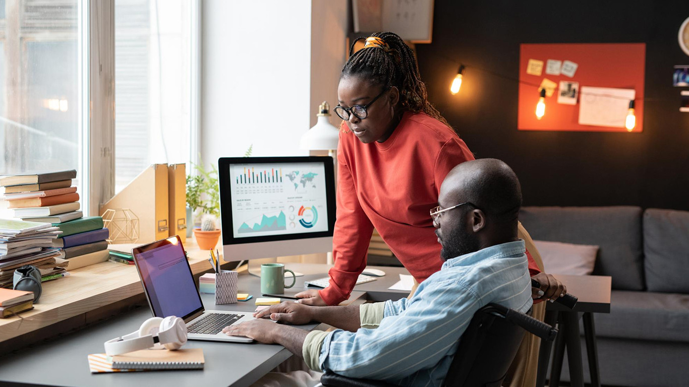 A diverse team of digital strategists gathering around a large, glowing interactive touch-table displaying website user behavior heatmaps, conversion data analytics, and user flow charts in a modern, dark-themed studio with user journey whiteboards in the background.