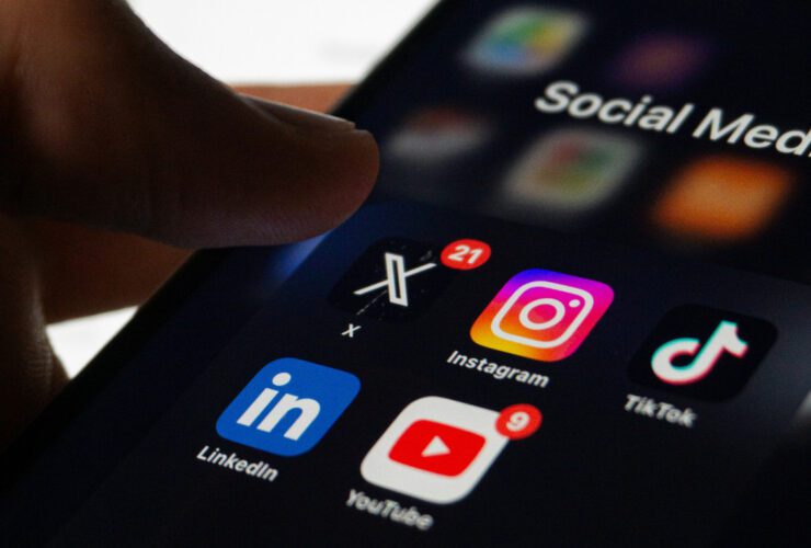 A small business owner looking at their smartphone, reviewing their social media feed with a thoughtful or frustrated expression, representing the challenge of building an audience without a clear content strategy.