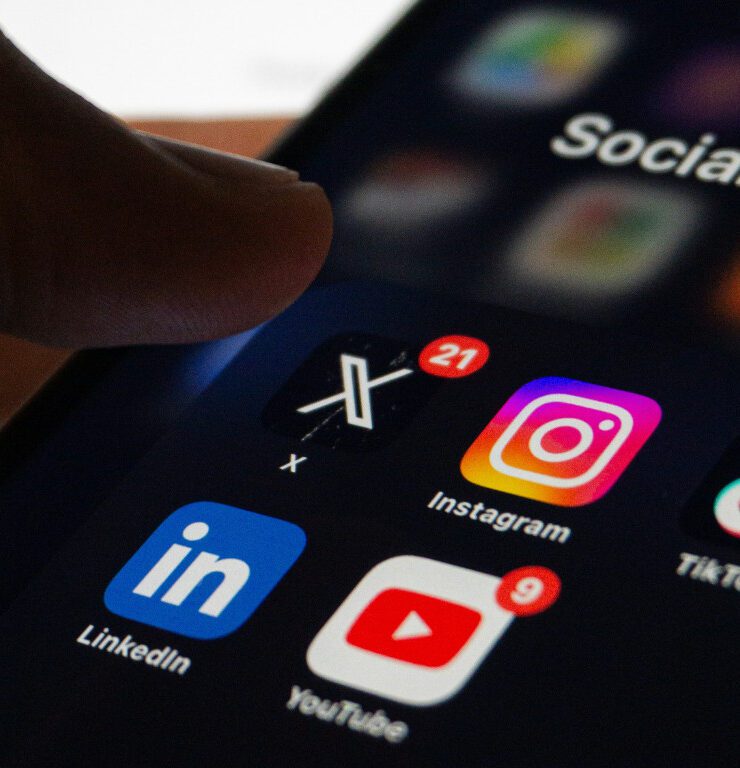 A small business owner looking at their smartphone, reviewing their social media feed with a thoughtful or frustrated expression, representing the challenge of building an audience without a clear content strategy.