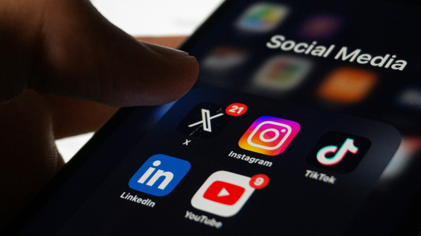 A small business owner looking at their smartphone, reviewing their social media feed with a thoughtful or frustrated expression, representing the challenge of building an audience without a clear content strategy.