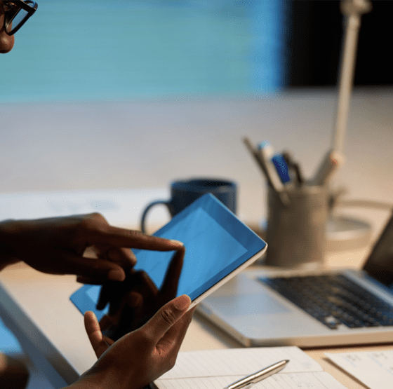 A business professional using a tablet and laptop to manage digital work, illustrating the importance of a cohesive digital strategy for growing businesses beyond simply being active online.
