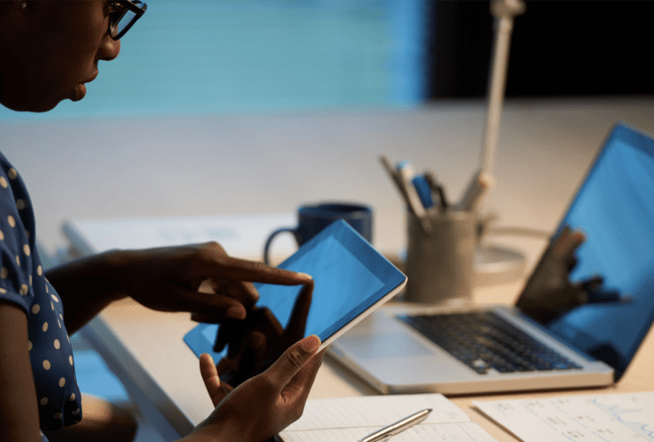 A business professional using a tablet and laptop to manage digital work, illustrating the importance of a cohesive digital strategy for growing businesses beyond simply being active online.