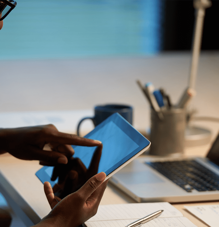 A business professional using a tablet and laptop to manage digital work, illustrating the importance of a cohesive digital strategy for growing businesses beyond simply being active online.