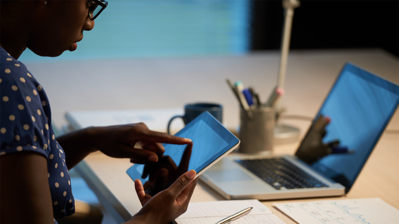 A business professional using a tablet and laptop to manage digital work, illustrating the importance of a cohesive digital strategy for growing businesses beyond simply being active online.